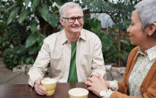 Happy senior couple sharing coffee and conversation in a lush garden setting.