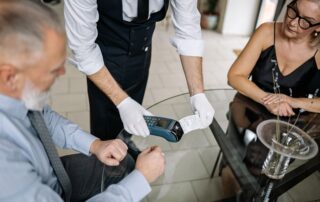 A couple making a contactless payment using a credit card at a restaurant table.