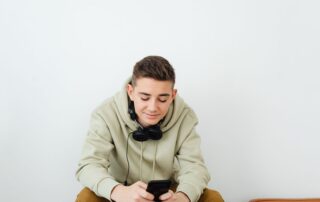 Young person enjoying technology, wearing casual clothes and headphones.