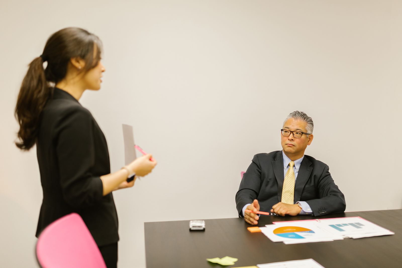 A professional woman presenting to a colleague during a business meeting in an office setting.