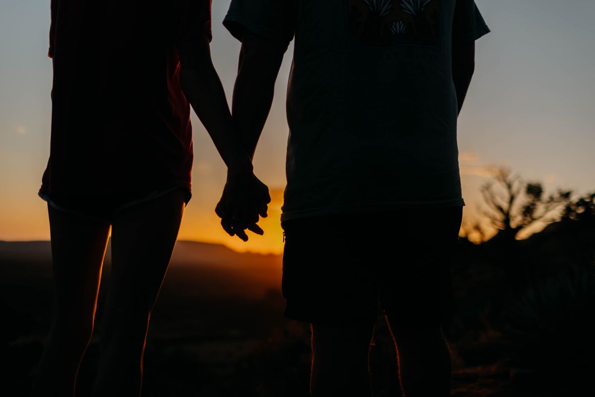 Silhouette of a couple holding hands at sunset
