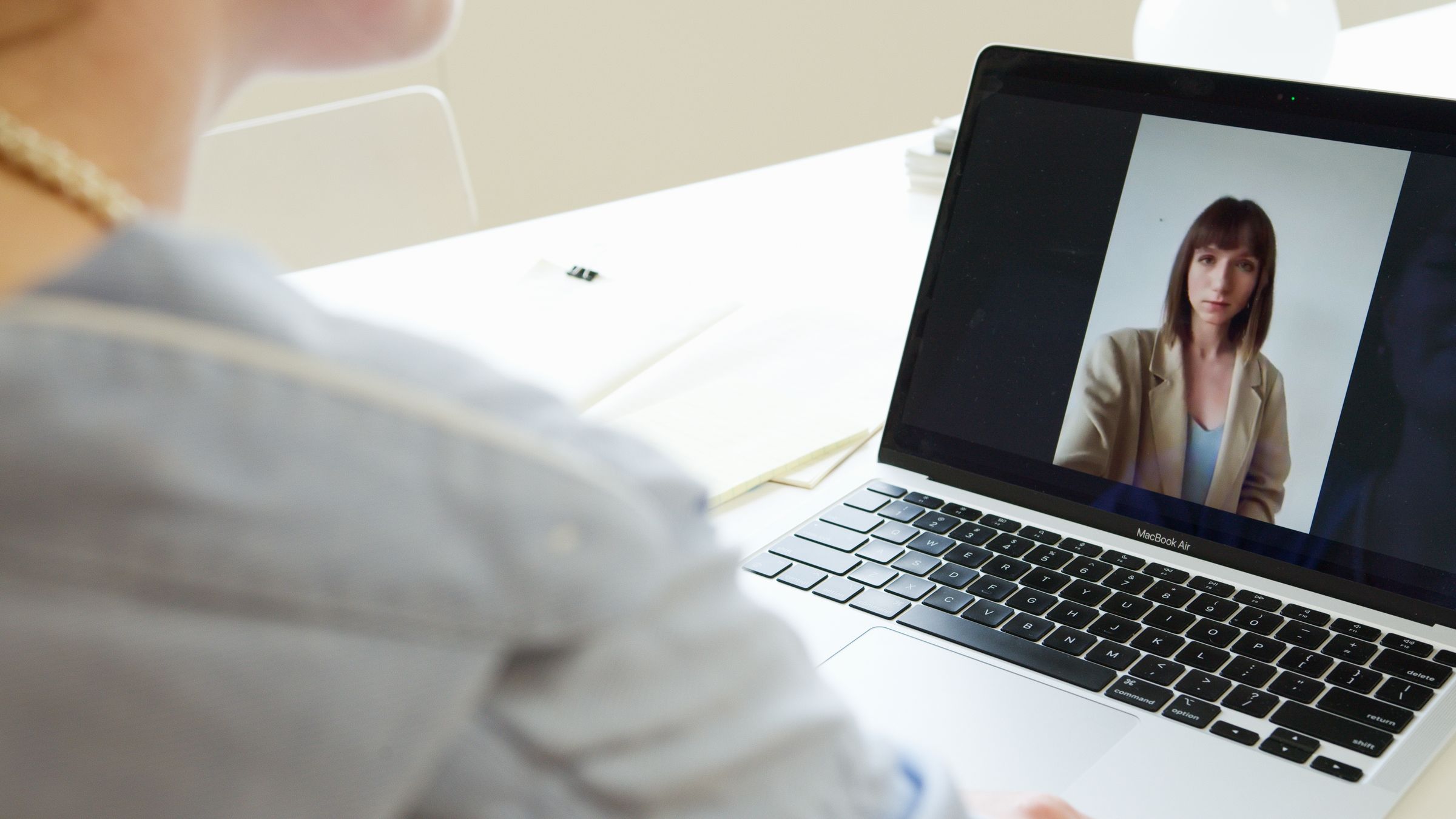 Close-up of woman on a video call using a laptop in a modern workspace.